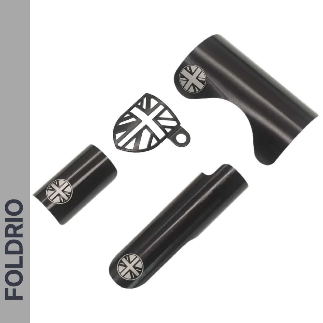 The FOLDRIO Brompton Frame Protector Set with British Flag is shown on a white background, featuring three black metal parts—including a rear fork cover and chainstay guard—each with a silver Union Jack bolt and FOLDRIO branding.