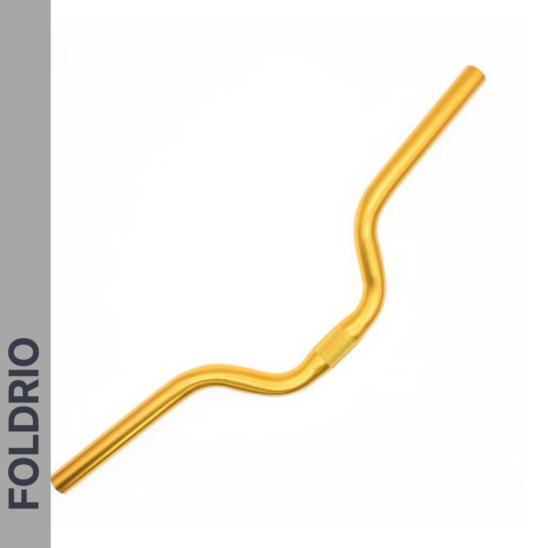 A gold Brompton M Handlebar – Anodised Aluminium, shown on a white background with a grey left bar featuring "FOLDRIO" in bold black letters, highlights its upright riding position. Available in 5 colours.