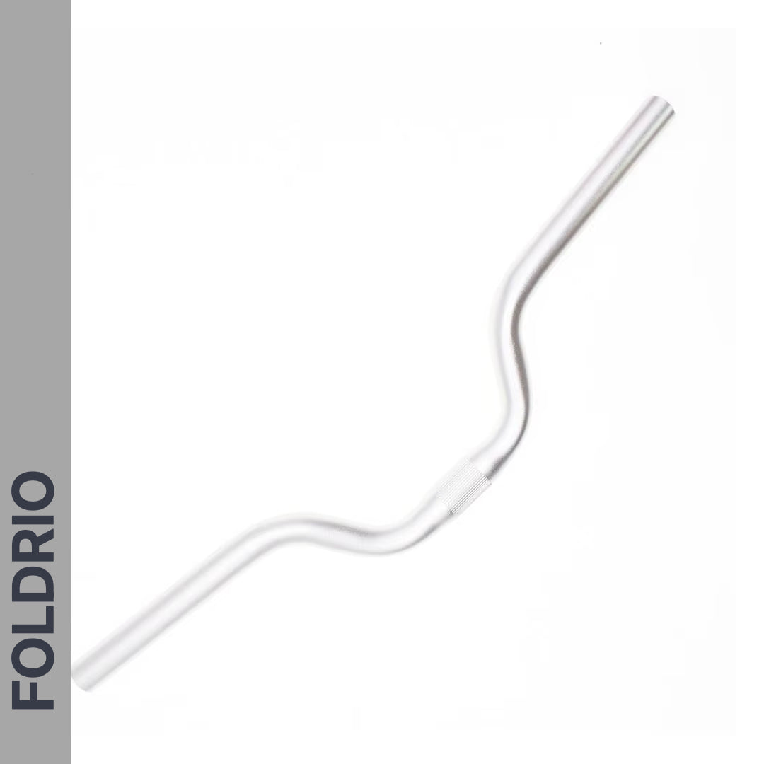 A Brompton M Handlebar – Anodised Aluminium, shown in silver with a gentle rise for upright riding, is placed diagonally on a white background. "FOLDRIO" appears vertically on a grey bar along the left side.