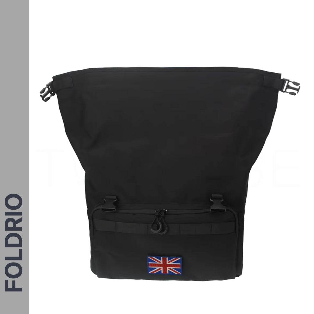 The FOLDRIO Brompton Roll-Top Front Bag – 27.5L is a black commuter and laptop backpack with a front zipper pocket and Union Jack patch, styled for Brompton bikes. "FOLDRIO" appears vertically on the left side of the image.