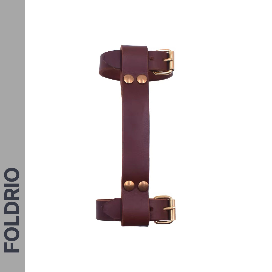 The FOLDRIO Brompton Leather Carry Handle – Full-Grain, Brass Hardware is shown vertically on a white background with FOLDRIO on a gray side strip. It features a brown leather handle, adjustable buckle straps, and brass rivets.