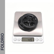 A black plastic pulley labeled FOLDRIO sits on a digital scale at 49.1g—ideal for those upgrading to Brompton Easy Wheels with Titanium Bolts or seeking lightweight alternatives.