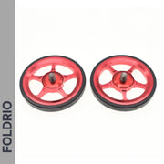 Two red metal Brompton Easy Wheels with black rubber edges and titanium bolts by FOLDRIO are displayed side by side on a white background. The FOLDRIO brand name appears vertically along the left.