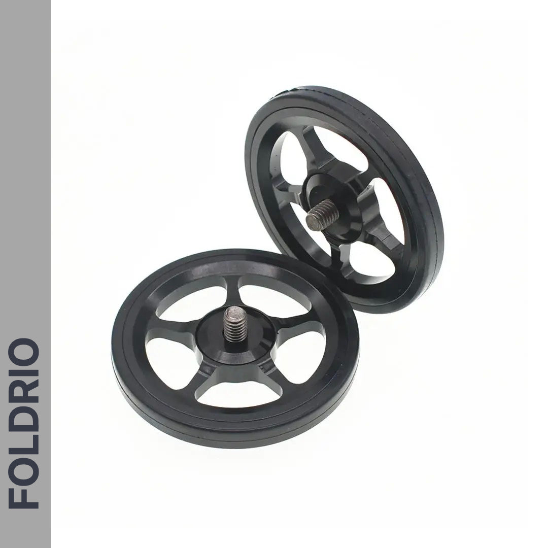 Two black, round Brompton Easy Wheels with five spokes and titanium bolts are shown on a white background. FOLDRIO branding appears vertically on a gray sidebar, highlighting these ultra-light bike accessories.