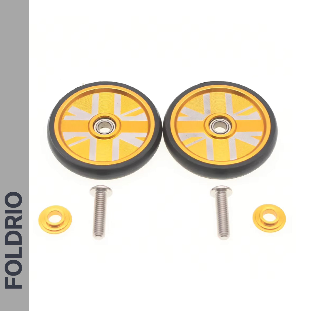 Two gold and black FOLDRIO Brompton Easy Wheels Union Jack Edition with titanium bolts and washers are displayed on a white background, with "FOLDRIO" vertically on the left.