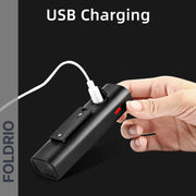 A hand holds the FOLDRIO Brompton Front Fork Light—400 lumen, adjustable beam—charging with a white USB-C cable. The screen shows “USB Charging” and the FOLDRIO logo, highlighting its power and rechargeable feature.