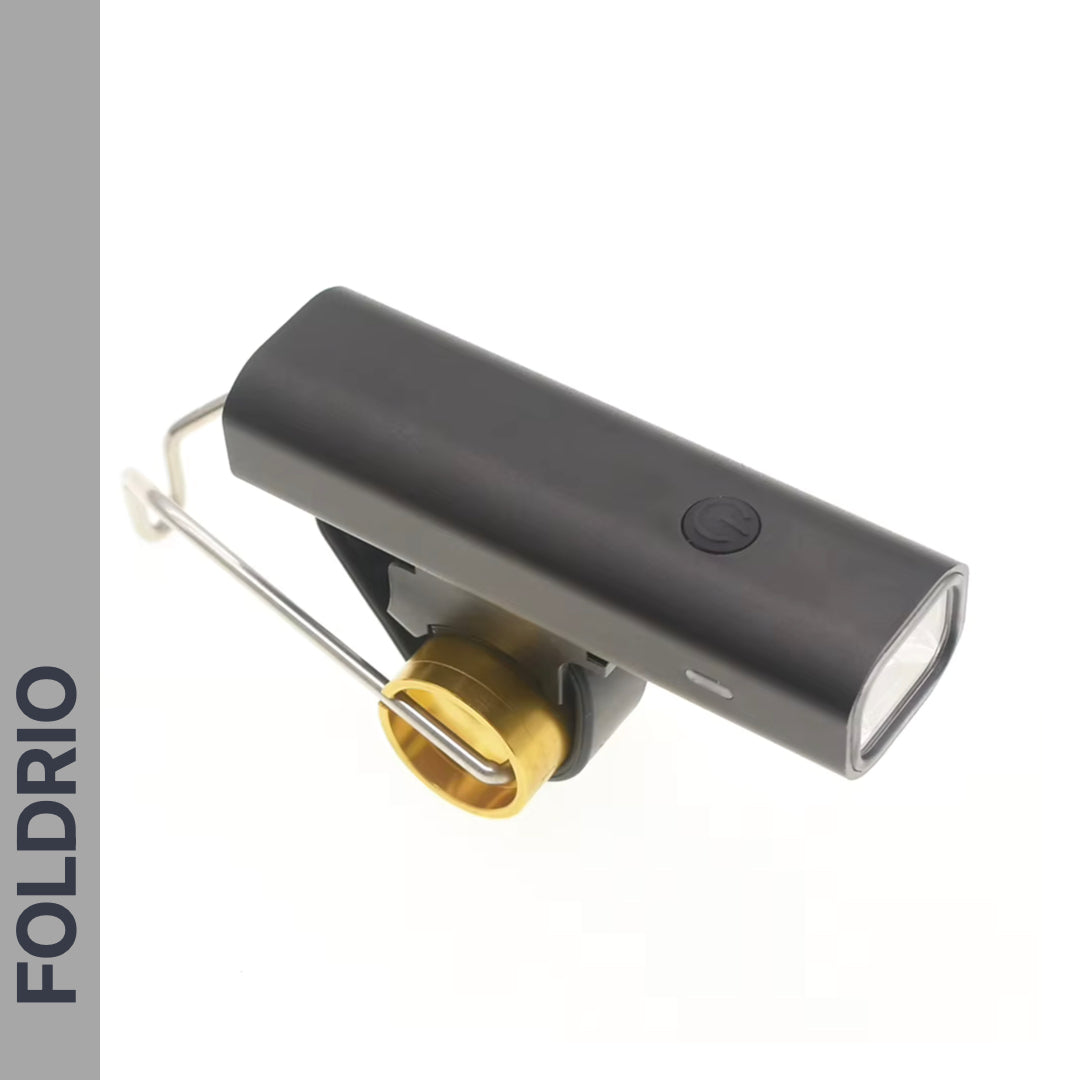 The FOLDRIO Brompton Front Fork Light features a black and gold rectangular design, 400 lumens brightness, adjustable beam, top power button, metal bracket mount, and “FOLDRIO” vertically on the left. USB-C rechargeable.