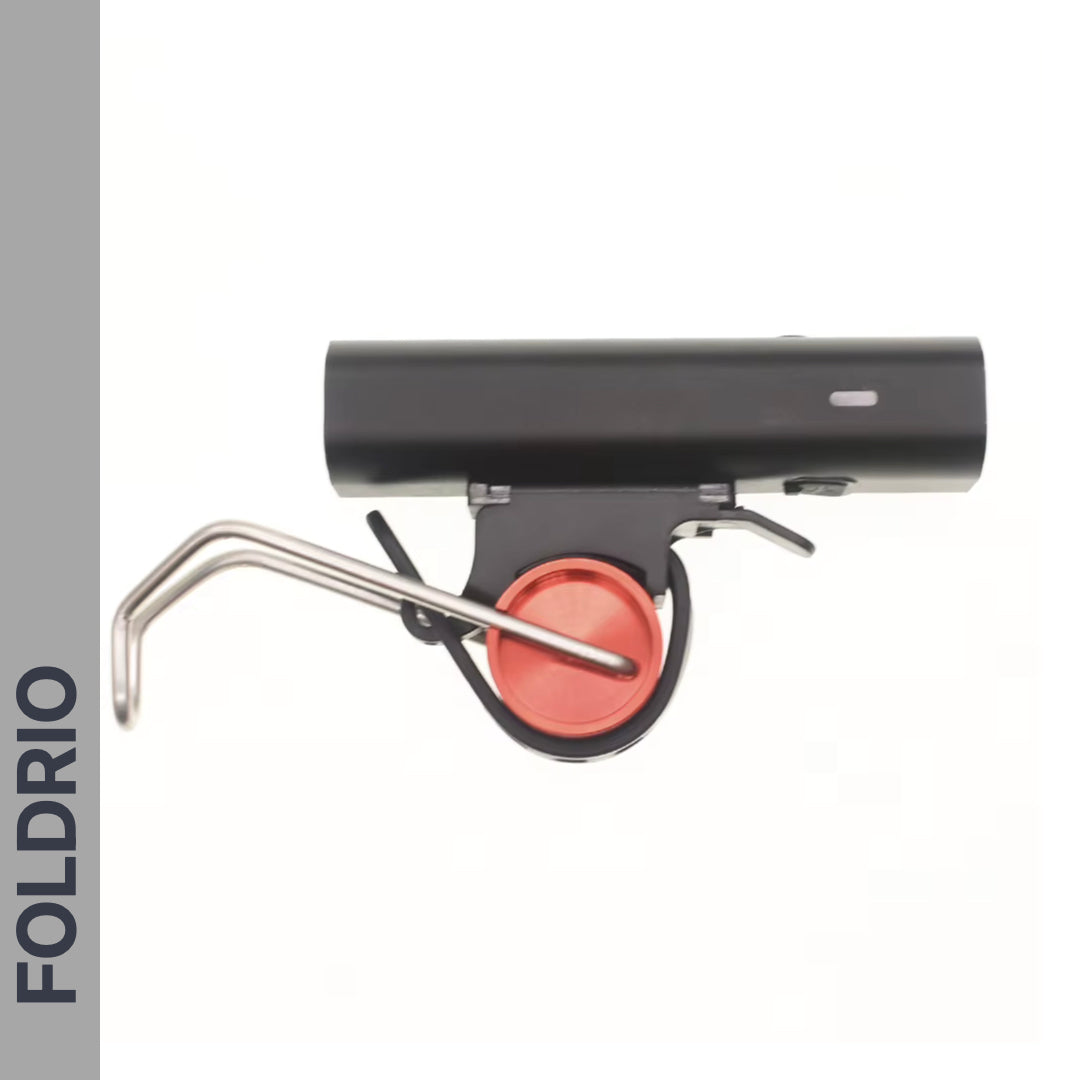 A black cylindrical FOLDRIO Brompton Front Fork Light – 400 Lumen, USB-C Rechargeable, with adjustable beam and red circular detail plus metal lever, is shown on a white background. FOLDRIO appears vertically on a gray strip at the left.
