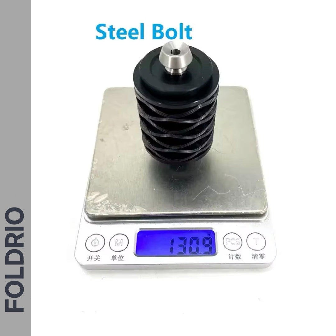 A Brompton Rear Shock Absorber by FOLDRIO is shown on a digital scale reading 130g. The product, in black and silver, is suitable for Brompton folding bikes. 'FOLDRIO' appears vertically on the left, with the product name above.