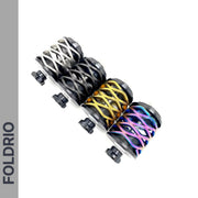 Four Brompton Rear Shock Absorbers by FOLDRIO, featuring crisscrossed spiral patterns in silver, black, gold, and rainbow colors, are displayed diagonally. The FOLDRIO logo appears vertically on a gray stripe to the left.
