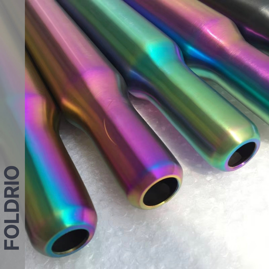Four Brompton Titanium Seatpost – Multicolour Edition rods from FOLDRIO lie parallel on bubble wrap. The brand name “FOLDRIO” is displayed vertically on a grey band at the left.