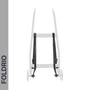 A partially visible wheeled cart shows the FOLDRIO brand vertically on the left; two black Brompton Rear Rack Elastic Straps, designed for AC Line (old) & PT Line (new), stand out on the light gray frame, resembling luggage straps.