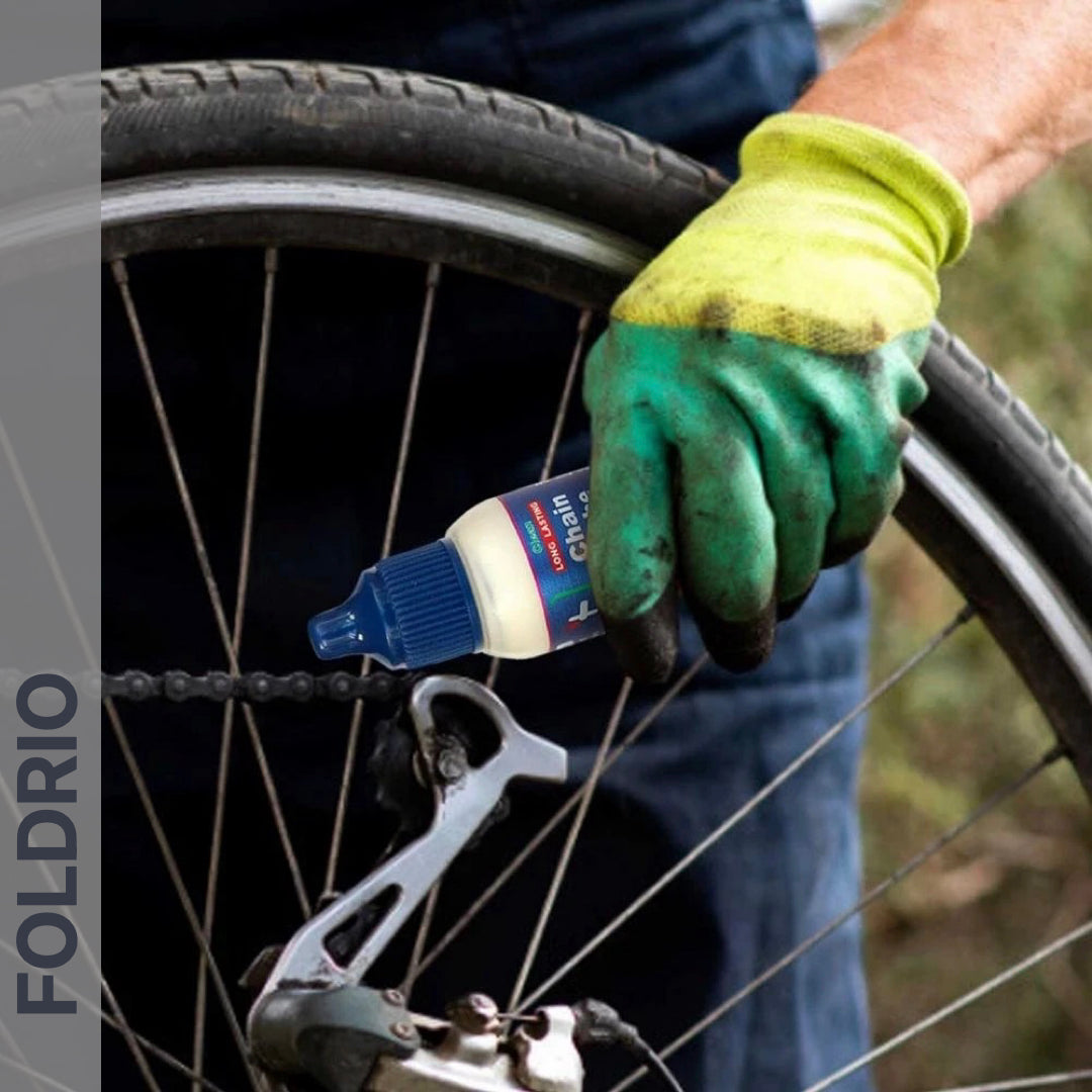 Brompton Brompton chain lube being applied with gloved hands to the chain, rear wheel and FOLDRIO branding visible | Foldrio. Foldrio
