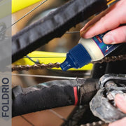 Brompton Brompton chain lube being applied to a bike chain near the pedal, FOLDRIO bottle visible, FOLDRIO branding left side | Foldrio. Foldrio