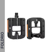 Two black Brompton Foldable Flat Pedals – Lightweight Aluminium Upgrade with rectangular cutouts and orange reflectors are shown, one facing forward and one in side view. "FOLDRIO" is vertically displayed on the left side of the image.