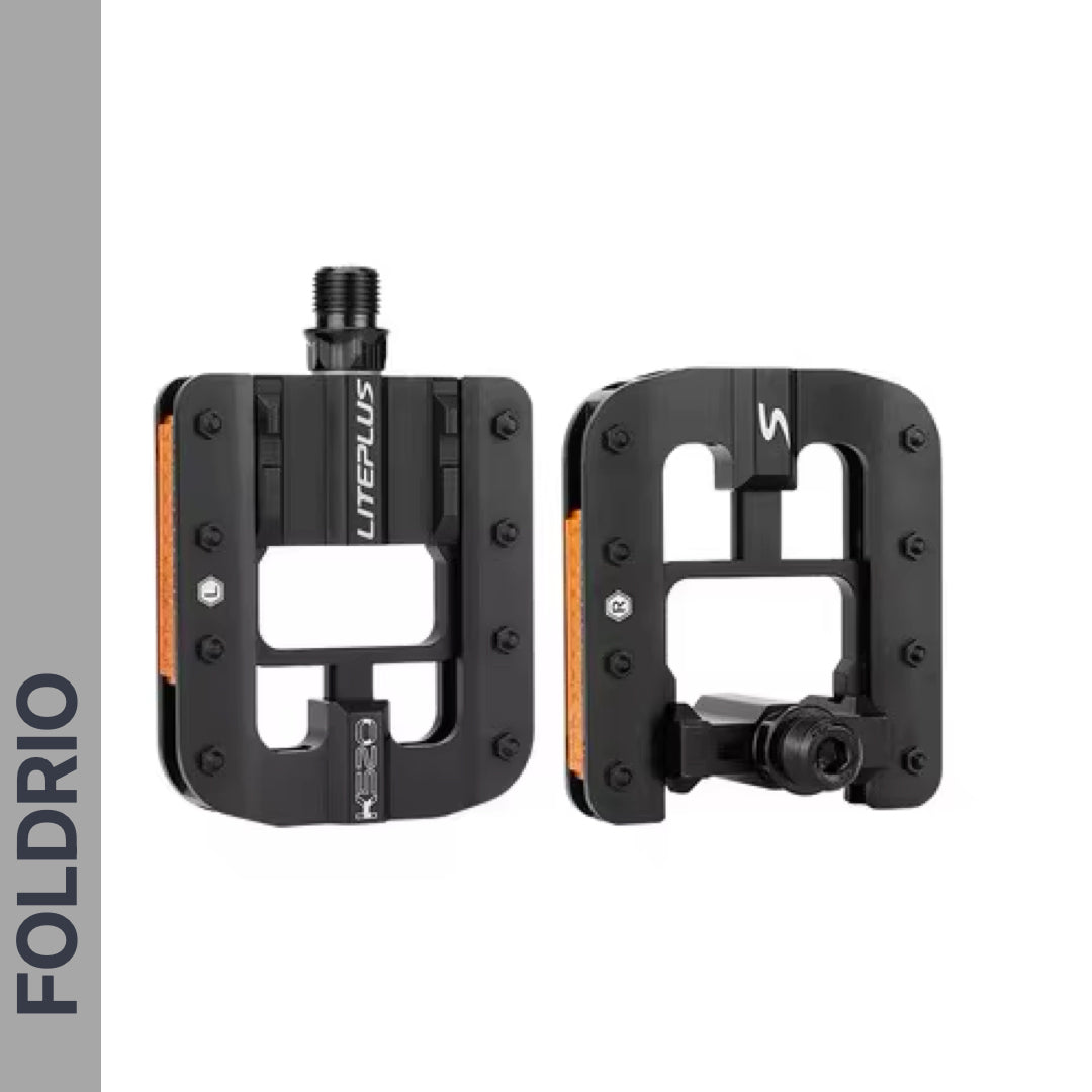 Two black Brompton Foldable Flat Pedals – Lightweight Aluminium Upgrade with rectangular cutouts and orange reflectors are shown, one facing forward and one in side view. "FOLDRIO" is vertically displayed on the left side of the image.