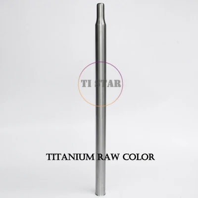 A metallic, cylindrical FOLDRIO Brompton Titanium Seatpost – Multicolour Edition stands upright against a plain white background. The text TITANIUM RAW COLOR is written below the seatpost.